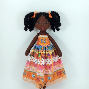 Little black doll in an orange dress, a gift for a girl, a decorative doll for room decoration