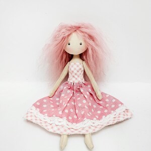 May include: A handmade doll with pink yarn hair, wearing a pink and white gingham dress with white polka dots and a white lace trim.
