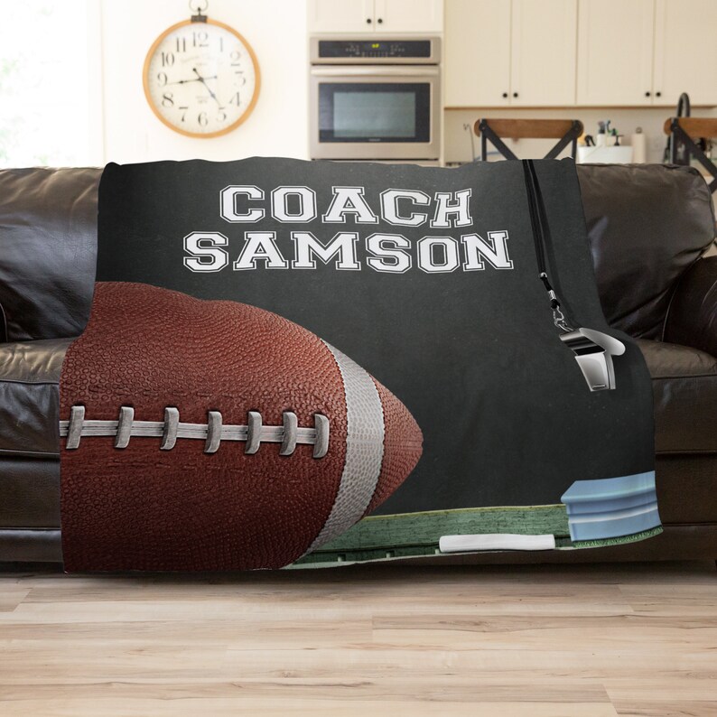 Pu&ograve; includere: Coperta in pile nera e bianca con un pallone da football e un fischietto. Il testo "COACH SAMSON" &egrave; scritto in bianco sulla coperta.
