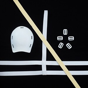 K&ouml;nnte beinhalten: Wei&szlig;er gepolsterter Helm mit drei Gurten und sechs wei&szlig;en Kunststoffschnallen. Die Gurte sind mit wei&szlig;en N&auml;hten am Helm befestigt.