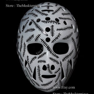 Peut inclure: Masque de gardien de hockey blanc avec un motif de couture noir. Le masque a une cage oculaire noire et une protection buccale noire. Le masque est un style populaire pour les joueurs de hockey.