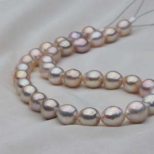May include: A strand of iridescent white pearls with a subtle pink hue. The pearls are strung on a thin white cord and are approximately 8mm in diameter.