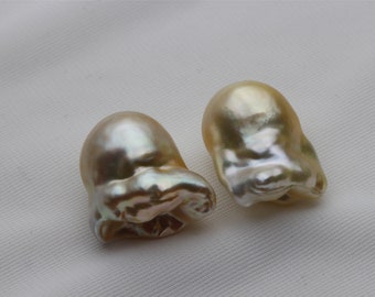 May include: Two large, irregular shaped, baroque pearls. The pearls are a pale golden color with iridescent highlights.