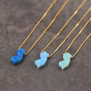 May include: Three gold necklaces with opal pendants shaped like the state of New Jersey. The pendants are in shades of blue and light blue.