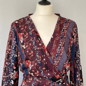 Peut inclure: Une robe longue à manches longues avec un col en V et un imprimé floral. La robe est faite d'un tissu doux et fluide et a une ceinture à la taille.