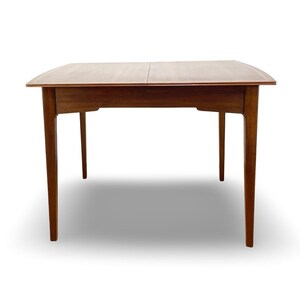 May include: A rectangular wooden dining table with a smooth, medium-brown finish. The table features a central seam indicating an extendable design, four tapered legs, and a clean, flat surface with slightly curved edges on the sides.