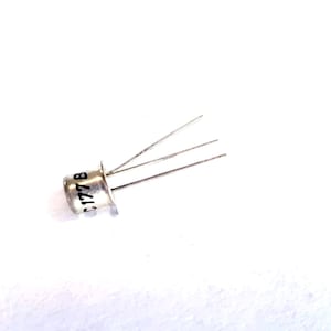 Pode incluir: Um componente de transistor de metal prateado com um corpo cilíndrico com o texto C177B impresso em preto. A peça eletrónica inclui três fios metálicos finos e retos que se estendem a partir da base da caixa cilíndrica.