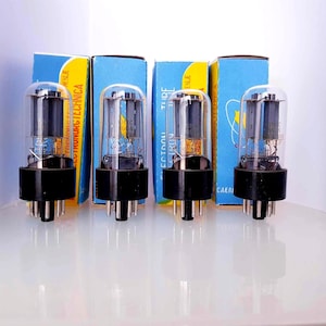 Puede incluir: Cuatro tubos de vacío con bombillas de vidrio transparente y bases negras se muestran frente a cajas azules. Las cajas tienen texto amarillo y blanco. Los tubos tienen pasadores plateados en la parte inferior.