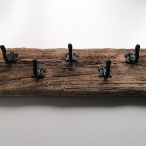 May include: A rustic wooden coat rack with five black metal hooks. The wood is weathered and has a natural finish.