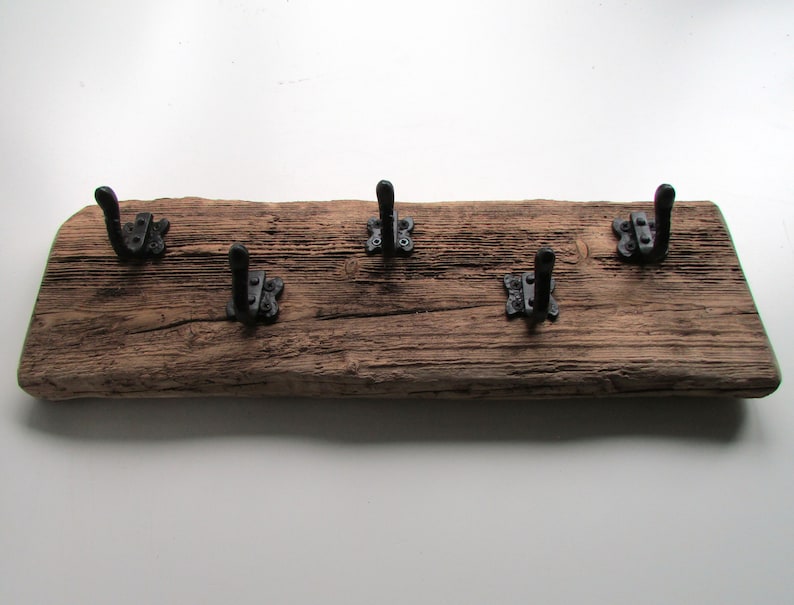 May include: A rustic wooden coat rack with five black metal hooks. The wood is weathered and has a natural finish.