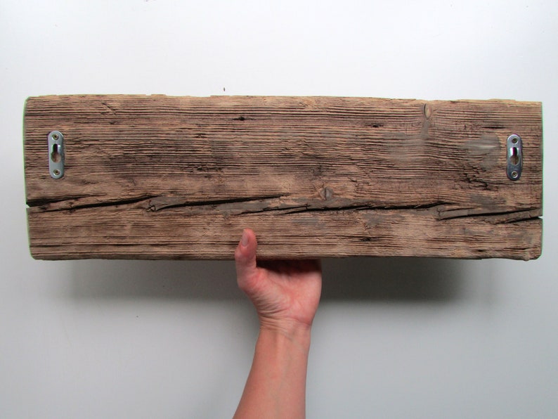 May include: A rustic wooden shelf with a natural brown finish and two metal hanging hooks. The shelf has a rough, weathered texture and is perfect for displaying decorative items.