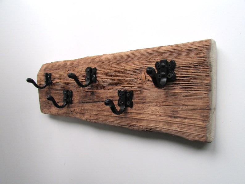 May include: A rustic wooden wall hook with four black metal hooks. The wood has a natural, weathered finish.