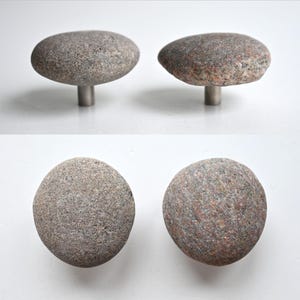 May include: Four stone cabinet knobs. Two knobs are shown from the side, revealing a mushroom-like shape with a grey stone top and a silver metal stem. The other two knobs are shown from above, displaying the round, textured stone surfaces.