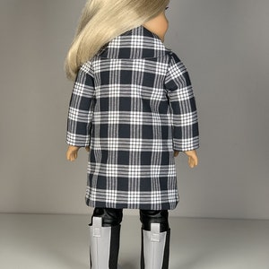 Pu&ograve; includere: Una bambola con un cappotto a quadri bianco e nero, leggings neri e stivali grigi. La bambola ha i capelli lunghi e biondi.