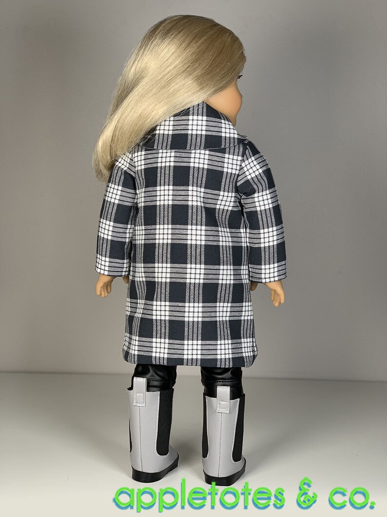 Pu&ograve; includere: Una bambola con un cappotto a quadri bianco e nero, leggings neri e stivali grigi. La bambola ha i capelli lunghi e biondi.