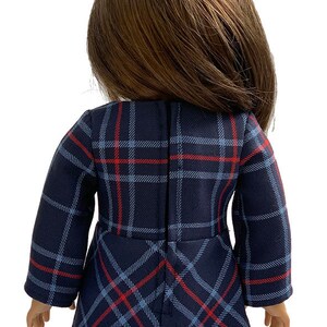 May include: A blue and red plaid dress with long sleeves for a doll. The dress has a zipper in the back.