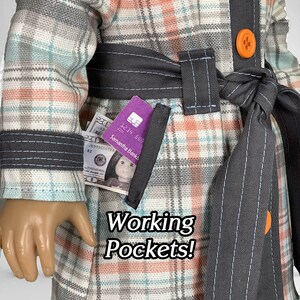 Puede incluir: Una chaqueta de cuadros con un cintur&oacute;n negro y botones naranjas. La chaqueta tiene un bolsillo con una tarjeta de cr&eacute;dito y dinero en efectivo en su interior. El texto "Working Pockets!" est&aacute; impreso en la chaqueta.