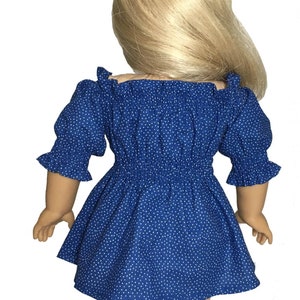 May include: A blue and white polka dot dress with a ruffled neckline and sleeves. The dress is made for a doll and has a fitted bodice and a flowing skirt. The dress is shown on a doll with blonde hair.