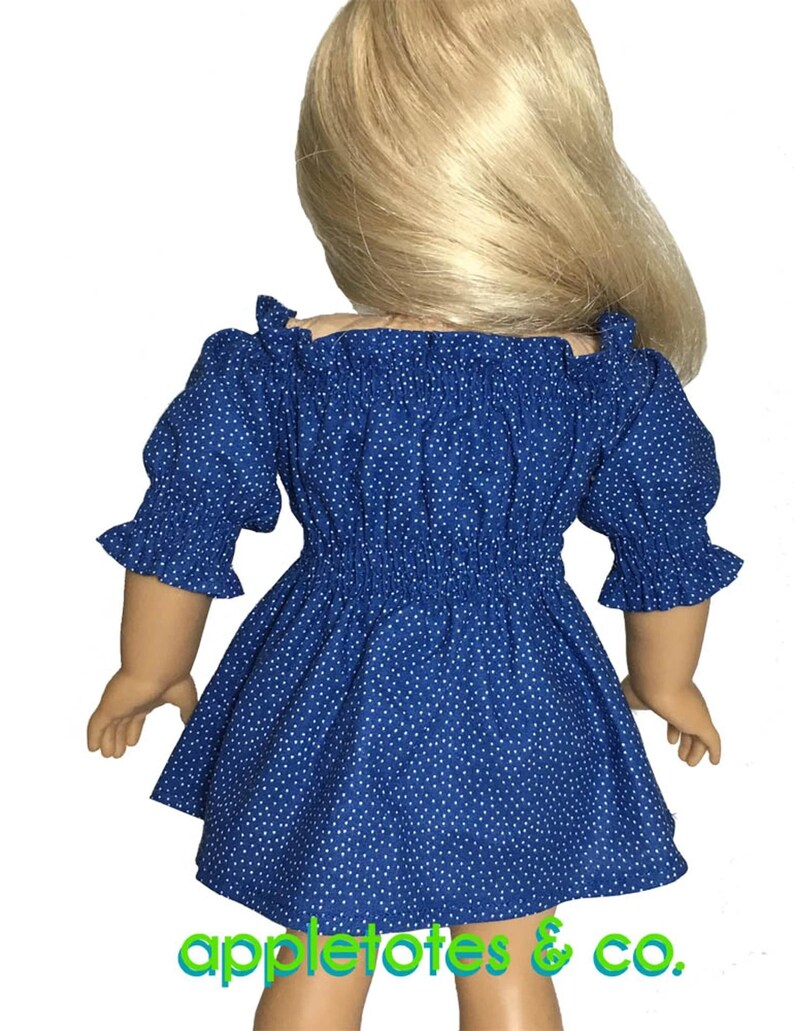 May include: A blue and white polka dot dress with a ruffled neckline and sleeves. The dress is made for a doll and has a fitted bodice and a flowing skirt. The dress is shown on a doll with blonde hair.