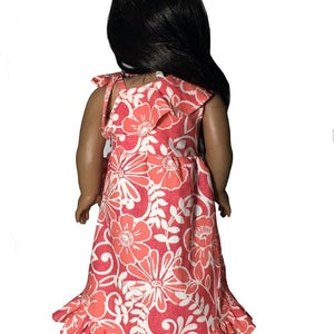 May include: A pink and white floral print dress with a ruffled hem and straps. The dress is designed for a doll.