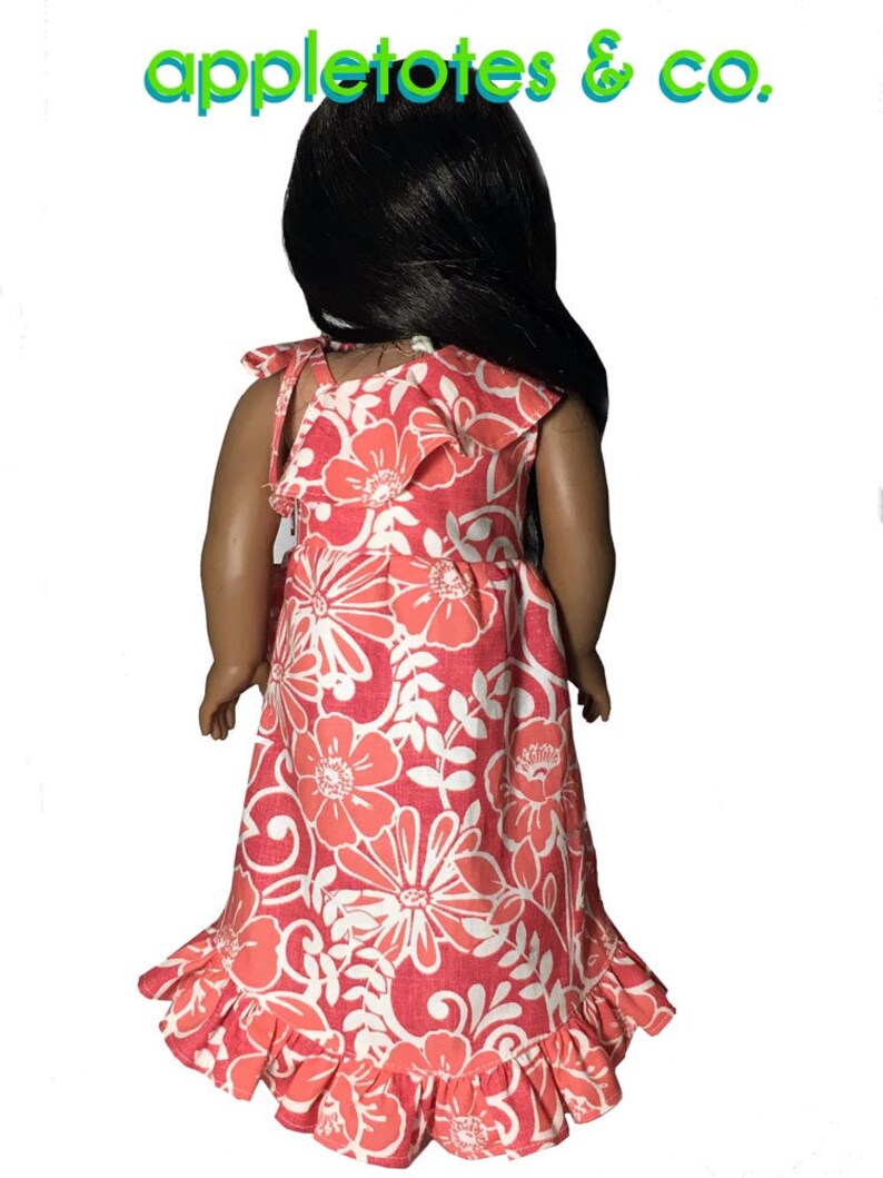 May include: A pink and white floral print dress with a ruffled hem and straps. The dress is designed for a doll.