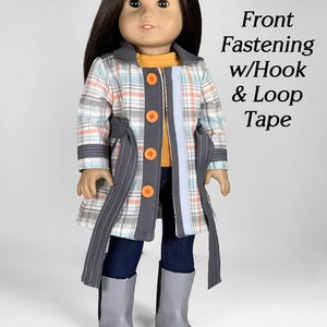 Puede incluir: Una mu&ntilde;eca con un abrigo de cuadros con ribetes grises y botones naranjas. El abrigo tiene un cintur&oacute;n y se cierra con velcro. La mu&ntilde;eca lleva pantalones vaqueros azules y botas grises. El texto "Front Fastening w/Hook & Loop Tape" es visible en la imagen.