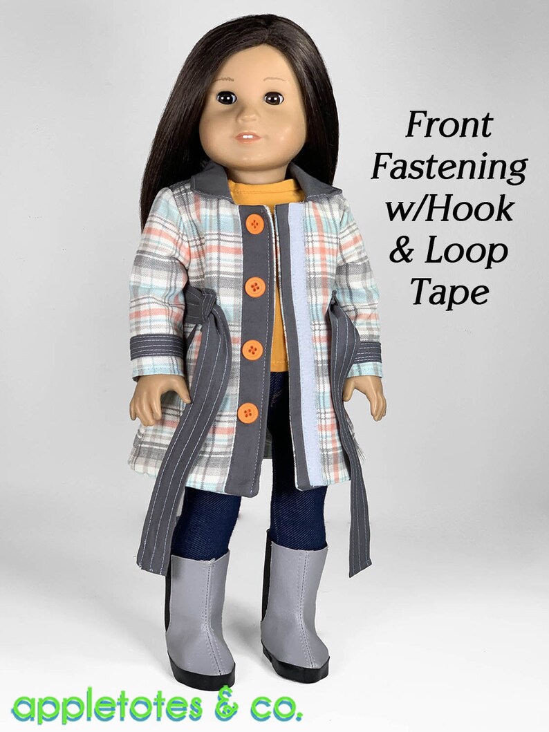 Puede incluir: Una mu&ntilde;eca con un abrigo de cuadros con ribetes grises y botones naranjas. El abrigo tiene un cintur&oacute;n y se cierra con velcro. La mu&ntilde;eca lleva pantalones vaqueros azules y botas grises. El texto "Front Fastening w/Hook & Loop Tape" es visible en la imagen.