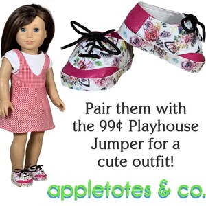 May include: A pair of pink and white floral sneakers with black laces. The sneakers are for a doll and are sitting on a white background. The text "Pair them with the 99&cent; Playhouse Jumper for a cute outfit! appletotes & co." is below the sneakers.