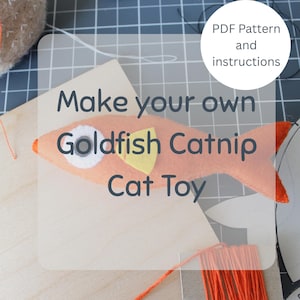 May include: An orange felt goldfish cat toy with a white eye and yellow fin is displayed. The text "Make your own Goldfish Catnip Cat Toy" is overlaid on the image. The words "PDF Pattern and instructions" are in a white circle.