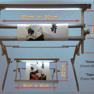 Puede incluir: Un bastidor de bordado de madera con luz LED integrada. El bastidor es ajustable para adaptarse a una pieza de tela de 60 cm o 90 cm de ancho. El bastidor tiene 30 cm de alto y una barra de soporte de 5 cm de ancho. El bastidor se muestra con una pieza de tela con un dise&ntilde;o de gr&uacute;a y los caracteres chinos "壽" y "時".