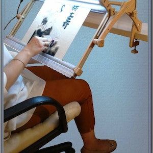 Puede incluir: Un soporte de aro de bordado de madera con una luz LED incorporada. El soporte est&aacute; sujeto a una mesa y tiene una tela blanca estirada sobre el aro. La tela tiene un dise&ntilde;o de bordado en blanco y negro de un mapache con el texto "Be Brave" bordado en &eacute;l.