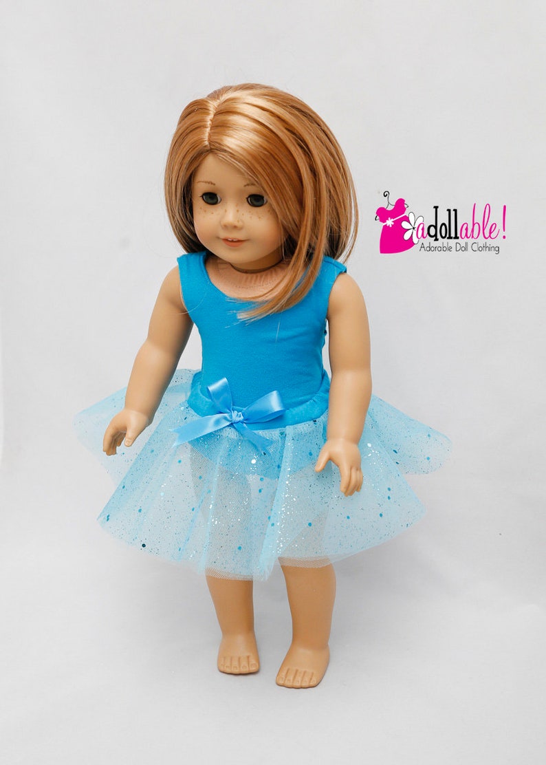 K&ouml;nnte beinhalten: Eine Puppe tr&auml;gt einen t&uuml;rkisfarbenen Trikot und einen hellblauen T&uuml;llrock mit silbernem Glitzer. Die Puppe hat langes, glattes, hellbraunes Haar und blaue Augen. Die Puppe steht auf einem wei&szlig;en Hintergrund. Das Bild enth&auml;lt den Text "a dollable! Adorable Doll Clothing".