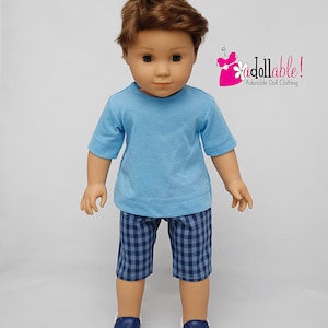 May include: A doll wearing a light blue t-shirt, blue and white plaid shorts, and dark blue sneakers. The doll has brown hair and blue eyes. The image includes the text "i dollable! Adorable Doll Clothing".