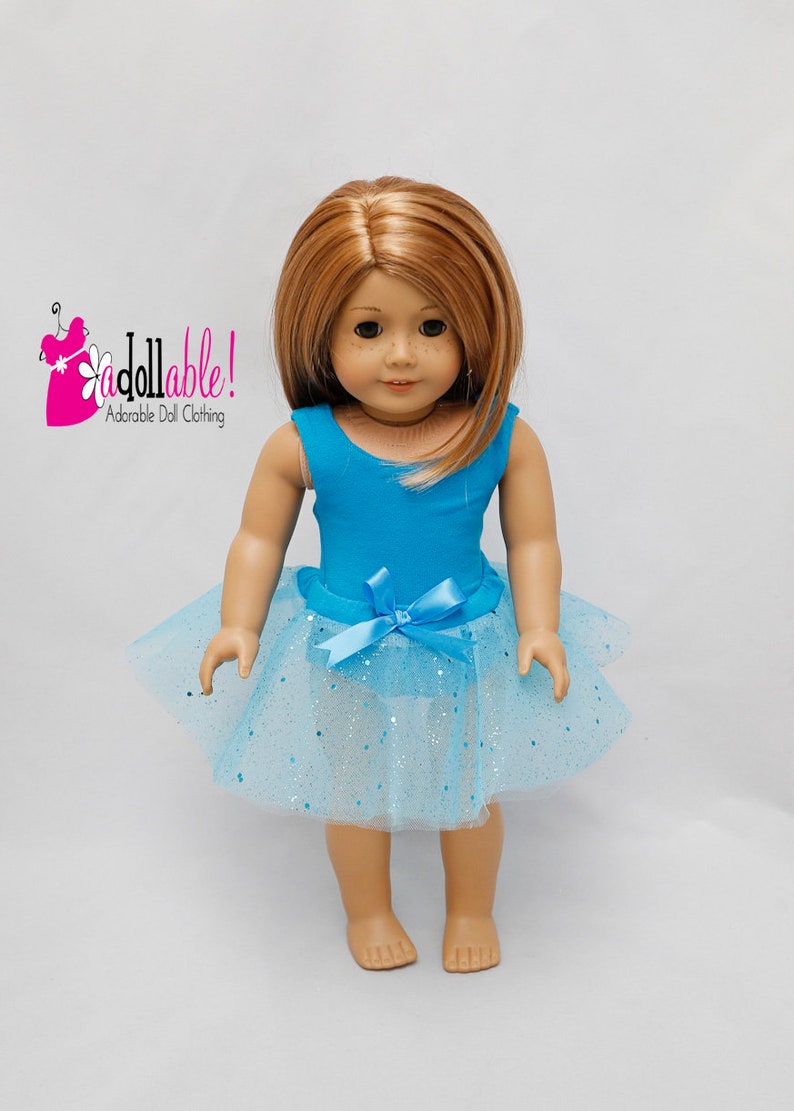 K&ouml;nnte beinhalten: Eine Puppe tr&auml;gt einen t&uuml;rkisfarbenen Trikot und einen hellblauen T&uuml;llrock mit silbernen Glitzer. Die Puppe hat langes, glattes, hellbraunes Haar.