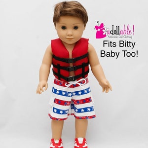 Puede incluir: Una muñeca con un chaleco salvavidas rojo con correas negras, pantalones cortos a rayas azules y blancas con estrellas blancas y zapatillas rojas. La muñeca tiene el pelo castaño y los ojos azules. El texto "Adorable! Adorable Doll Clothing Fits Bitty Baby Too!" está en la esquina superior derecha de la imagen.