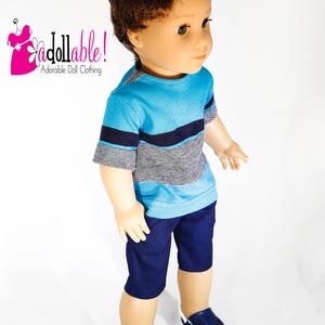 K&ouml;nnte beinhalten: Eine Puppe tr&auml;gt ein kurz&auml;rmliges Shirt mit blau-wei&szlig;en Streifen, eine dunkelblaue Shorts und blaue Turnschuhe.
