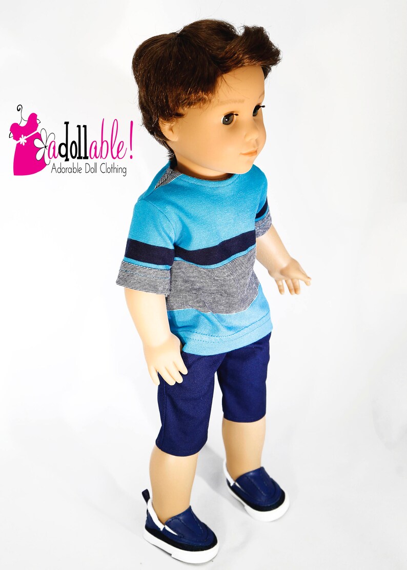 K&ouml;nnte beinhalten: Eine Puppe tr&auml;gt ein kurz&auml;rmliges Shirt mit blau-wei&szlig;en Streifen, eine dunkelblaue Shorts und blaue Turnschuhe.
