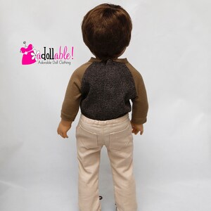 May include: A doll wearing a brown and grey long-sleeved shirt with a brown and beige pair of trousers. The doll is facing away from the camera. The text "Addollable! Adorable Doll Clothing" is visible in the top left corner of the image.