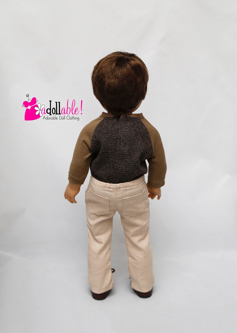 May include: A doll wearing a brown and grey long-sleeved shirt with a brown and beige pair of trousers. The doll is facing away from the camera. The text "Addollable! Adorable Doll Clothing" is visible in the top left corner of the image.