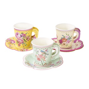 May include: Three paper teacups and saucers with floral designs. The cups have a yellow, cream, and green background with pink, purple, and blue flowers. The saucers have a matching floral design with pink, purple, and yellow accents.