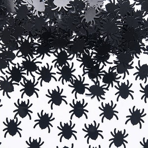May include: Black spider confetti, a scattering of small black spider cutouts on a white background.