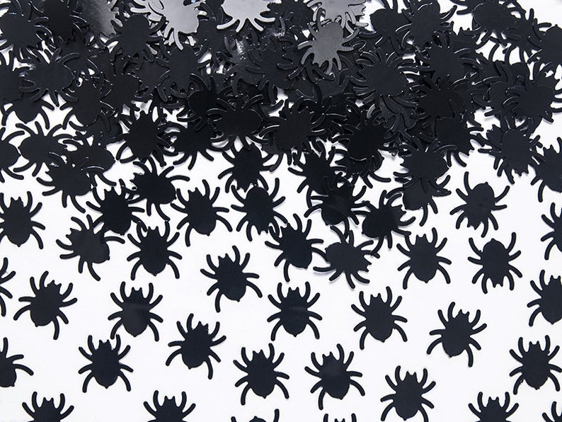 May include: Black spider confetti, a scattering of small black spider cutouts on a white background.