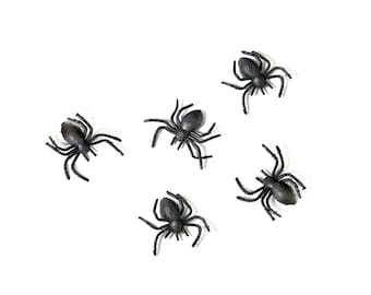 May include: Five black plastic spiders on a white background. The spiders have eight legs and are arranged in a semi-circle.