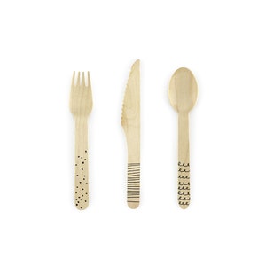 May include: A set of three wooden cutlery pieces, a fork, a knife, and a spoon, with black and white patterned designs. The fork has a black polka dot pattern, the knife has a black stripe pattern, and the spoon has a black wavy line pattern.