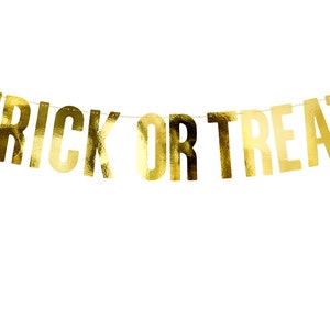 May include: Gold foil banner with the words "Trick or Treat" hanging on a white background.