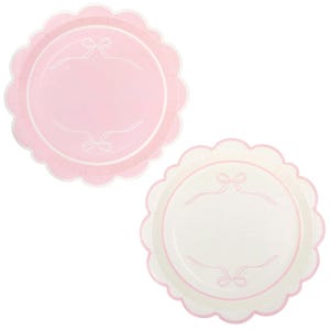 May include: Two scalloped-edge paper plates. One is solid pink, the other is white. Both plates have a light pink border and a central design featuring a bow and ribbon motif. The plates are designed for a party or event.