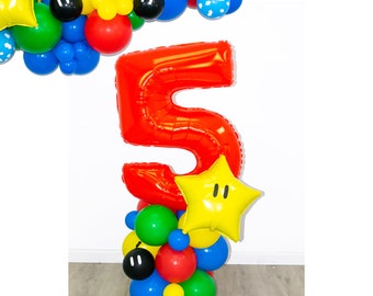 May include: A red number 5 balloon with a yellow star balloon with a black face. The balloons are surrounded by smaller balloons in various colors, including red, yellow, blue, green, and black.
