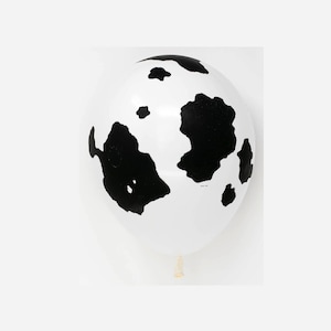 May include: A white balloon with black cow print spots.