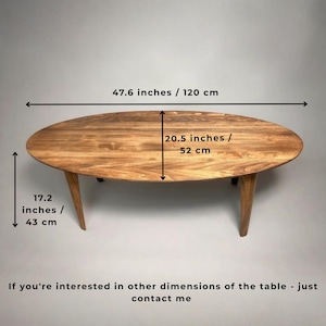 May include: Oval wooden coffee table with three angled legs. The table is 47.6 inches long, 20.5 inches wide, and 17.2 inches high. The table has a natural wood grain finish.