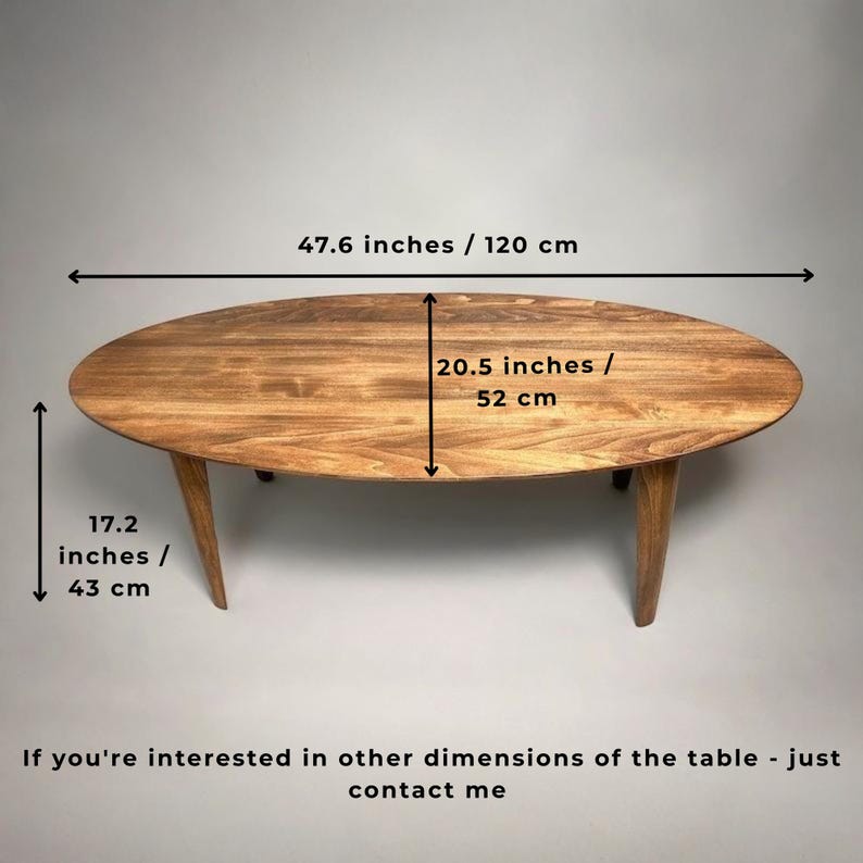 May include: Oval wooden coffee table with three angled legs. The table is 47.6 inches long, 20.5 inches wide, and 17.2 inches high. The table has a natural wood grain finish.